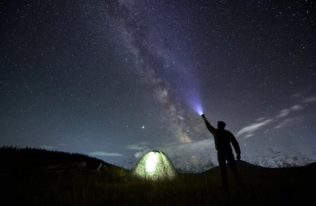 male flashlight into the night starry sky